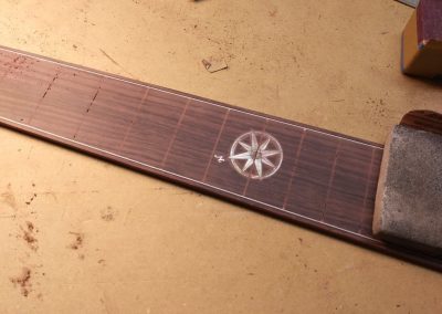 Fretboard being fine sanded and prepared before installing frets