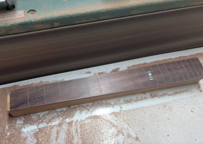 The fretboard is being radiused on the edge sander